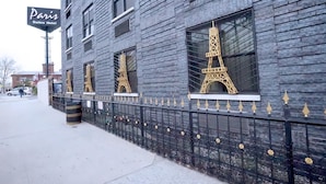 A building with a sign reading "Paris Suites Hotel" and windows featuring the Eiffel Tower design. - Paris Suites Hotel (Corona)