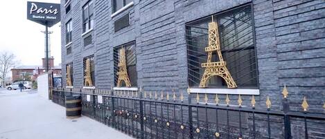 En byggnad med en skylt där det står ”Paris Suites Hotel” och fönster som har en design med Eiffeltornet.