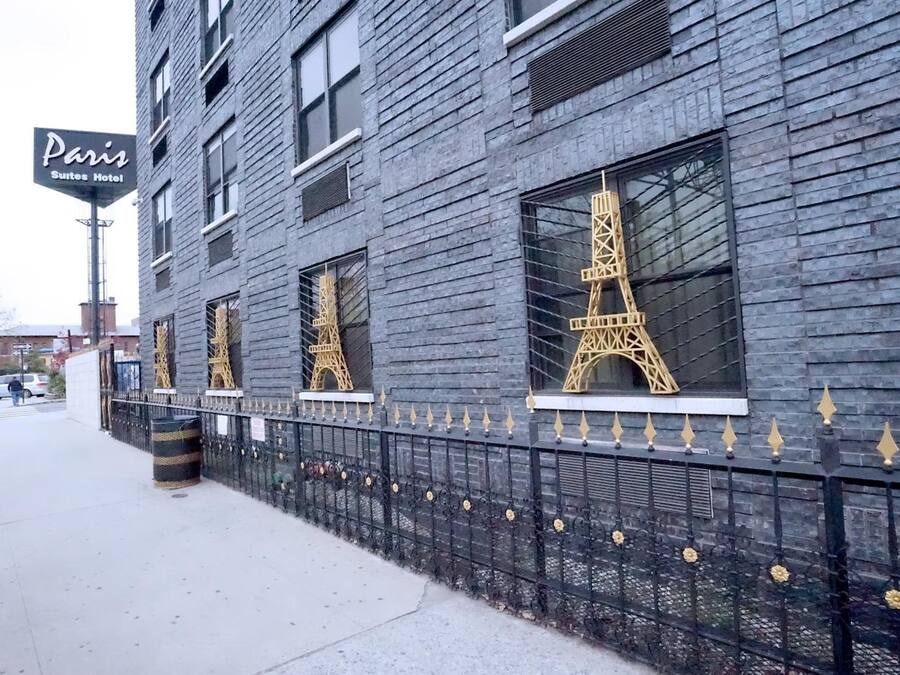 A building with a sign reading "Paris Suites Hotel" and windows featuring the Eiffel Tower design.