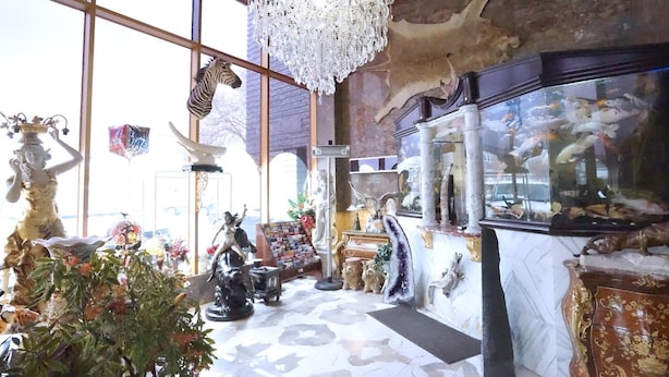 A room with a chandelier, large windows, and various statues and decorative items. - Paris Suites Hotel (Corona)