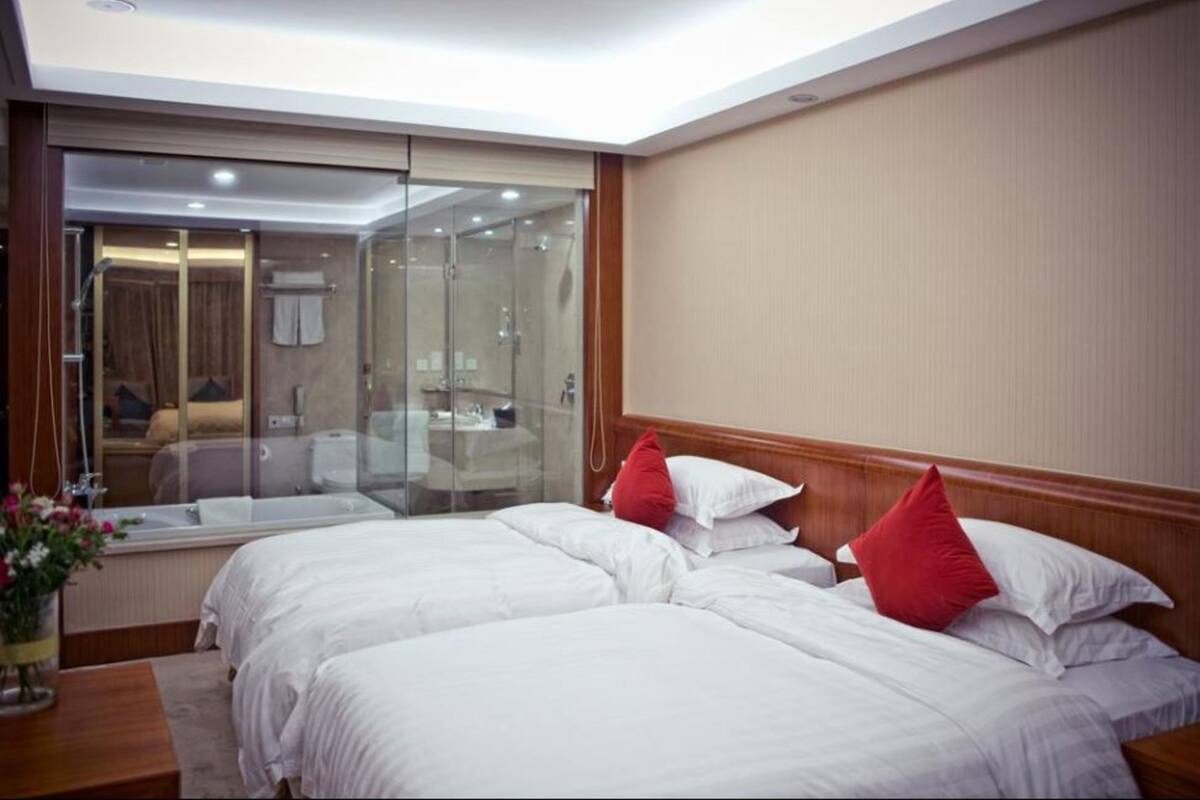 A hotel room with two beds, a large mirror, and a sliding glass door leading to a bathroom.