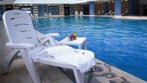 Une piscine intérieure avec des chaises longues blanches et une table sur laquelle sont posées des bouteilles.
