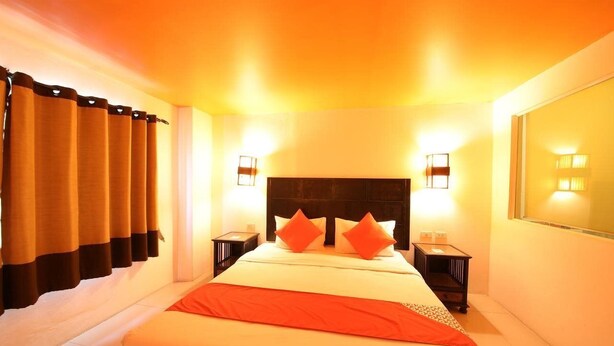 A hotel room with a large bed, two bedside tables, and a nightstand. - OYO 126 Patong Station House (Patong)