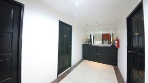 A hallway with black doors, a white wall, and a tiled floor. - OYO 126 Patong Station House (Patong)