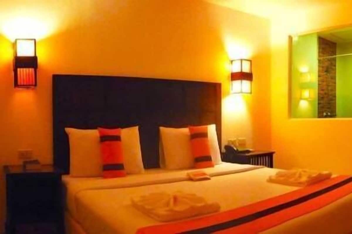 Una habitación de hotel con una cama grande, dos lámparas de noche, una mesita de noche y un espejo en la pared.