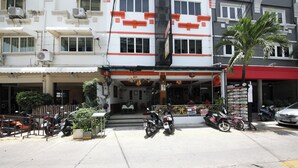 A building with multiple floors, air conditioning units, and a storefront with a sign. - OYO 126 Patong Station House (Patong)