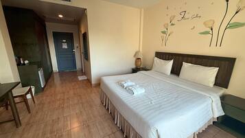 A hotel room with a large bed, a desk, and a chair. There is a wall with a floral design and a sign that says 'Flower Gallery'.