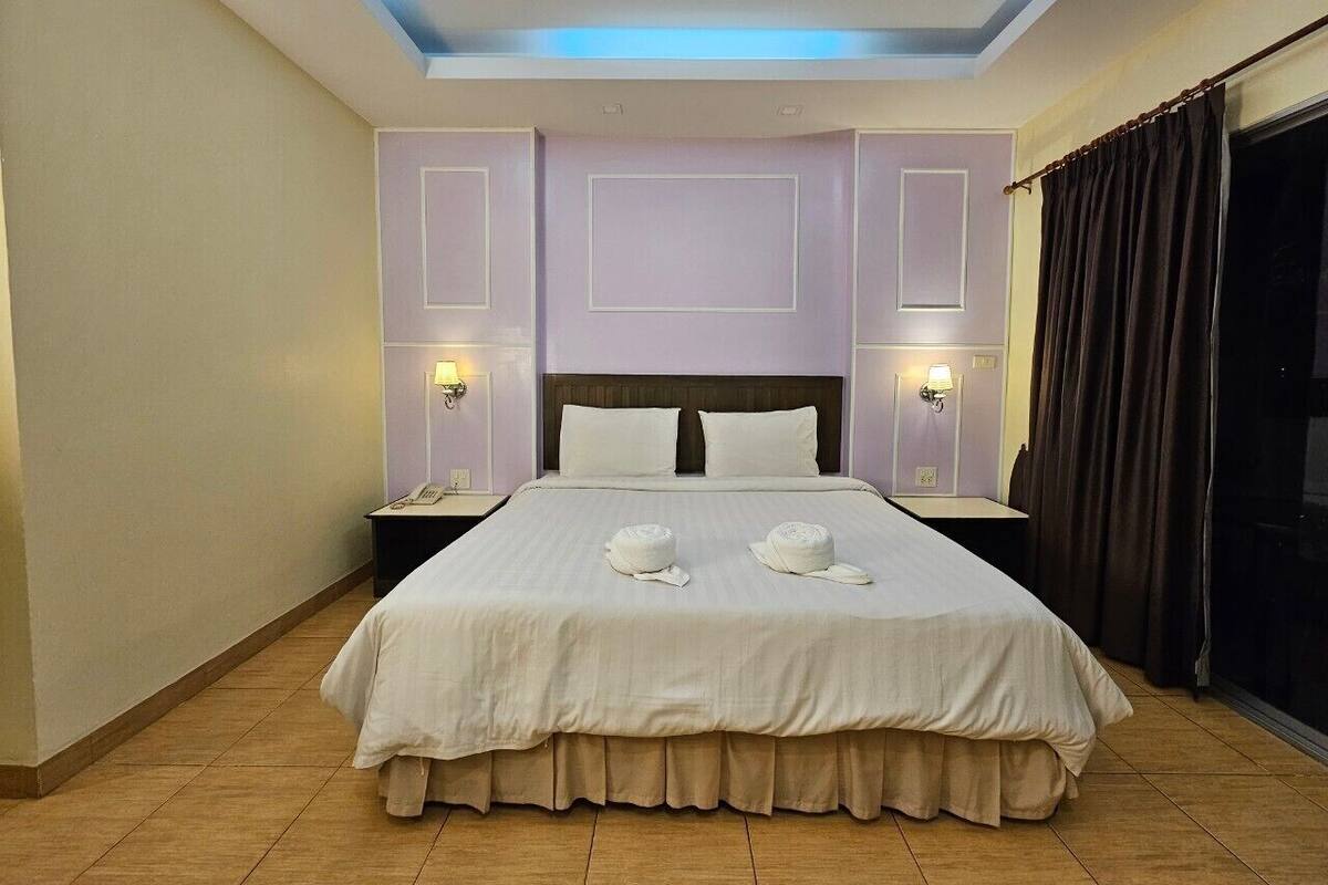 Een hotelkamer met een groot bed, twee bedlampen, een hoofdeinde en uitzicht op het omliggende landschap.