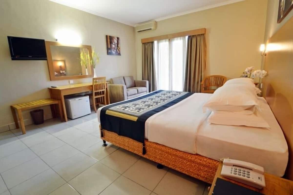 Una habitación de hotel con cama, escritorio, silla, televisor y teléfono.