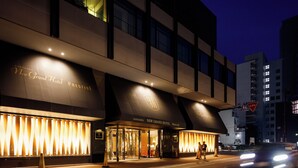 L’extérieur du New Grand Hotel se distingue par son entrée imposante et sa façade illuminée.