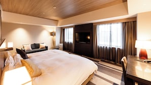 Une chambre d’hôtel avec un grand lit, un canapé, une télévision et un bureau avec une lampe.