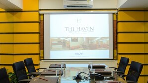 Una sala de conferencias con una pantalla grande mostrando 'THE HAVEN SERVICED RESIDENCES' y 'RISAN'.