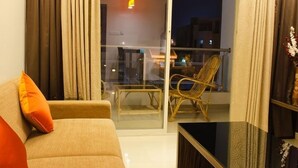 Una sala de estar con un sofá, un ventanal de vidrio que da a un balc ón con una silla y una mesa.