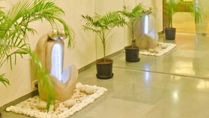 Un vestíbulo con una lámpara de araña moderna, plantas en macetas y una pieza decorativa en la pared.