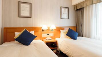 A hotel room with two beds, a nightstand with a phone, and framed pictures on the wall.