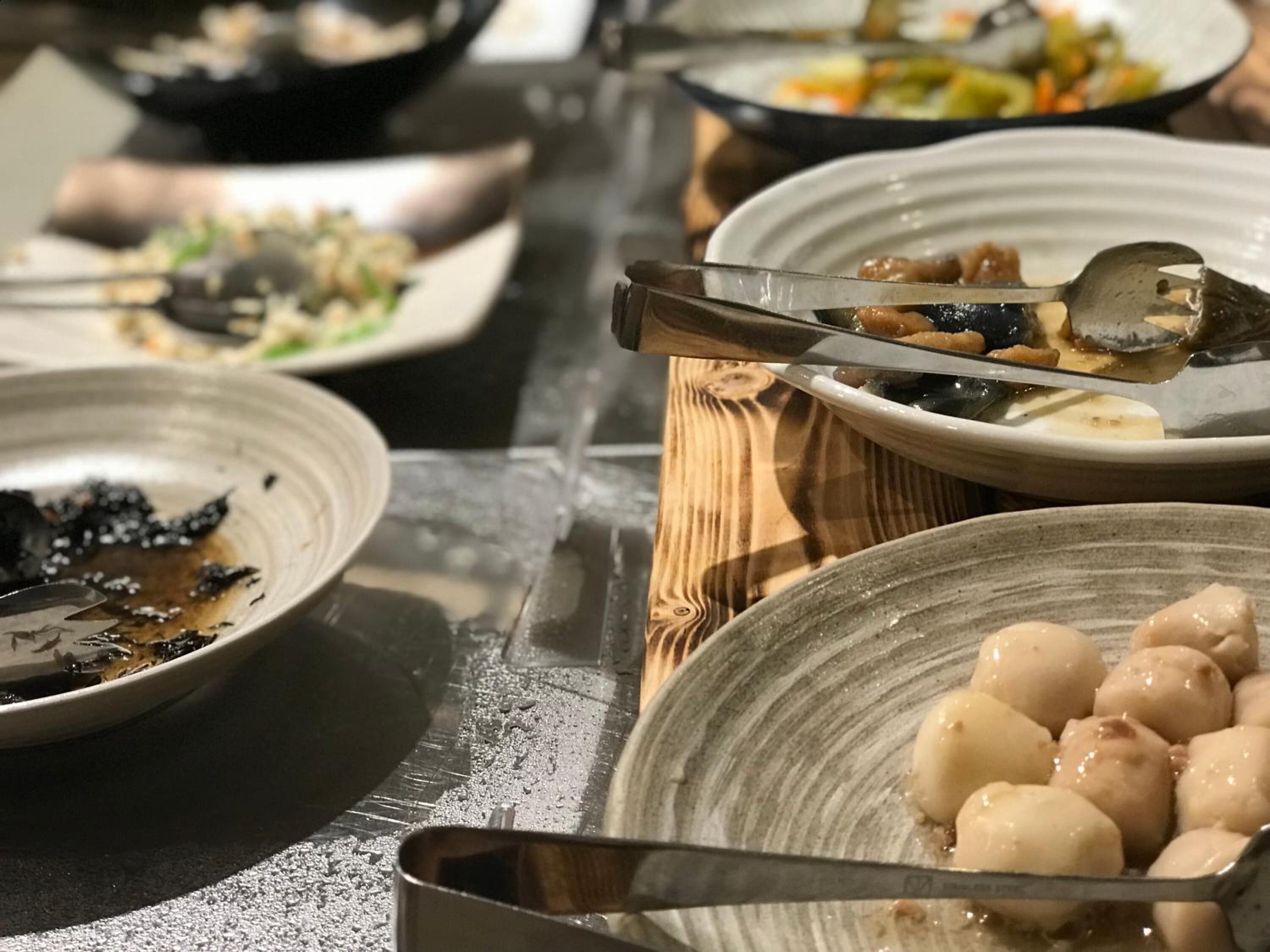 Une table à manger avec différents plats, notamment un bol de raviolis et une assiette avec une sauce foncée.