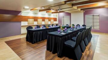 A conference room with long tables, black chairs, and a projector.