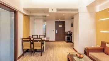 Quarto de hotel com área de refeições, cozinha compacta e sala de estar com uma tigela de frutas.