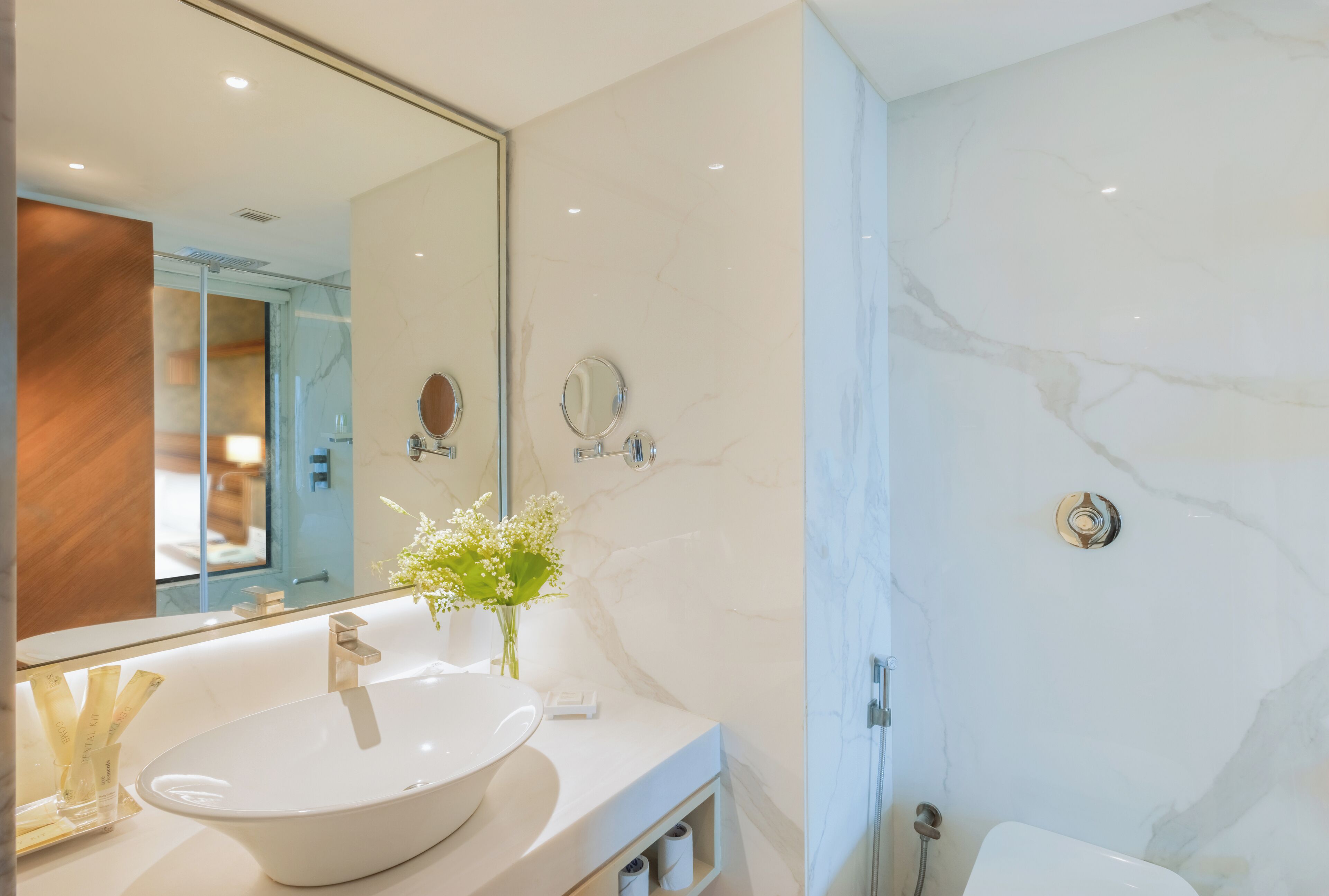 A modern bathroom with a large white sink, a mirror, and a shower area.