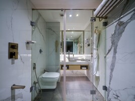 A modern bathroom with a glass shower enclosure, a toilet, and a vanity with a mirror.
