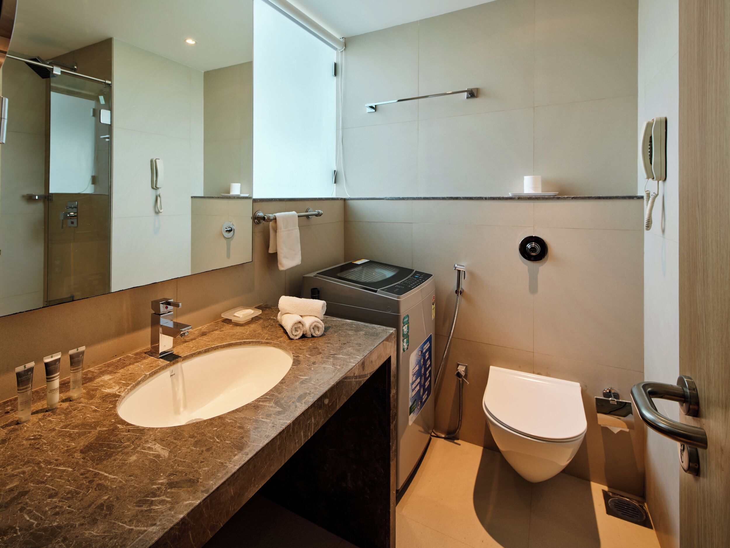 A modern bathroom with a large mirror, a sink, a toilet, and a shower.