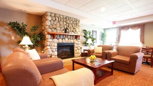 A hotel lobby with a stone fireplace, leather sofas, a coffee table, and a carpeted floor.