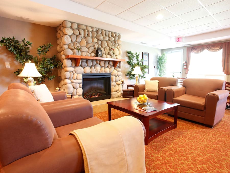 A hotel lobby with a stone fireplace, leather sofas, a coffee table, and a carpeted floor.