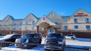 A hotel with a sign reading 'POOL WATERSLIDE' and 'COAST hotels' on the facade. There are three SUVs parked in front.