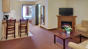 A living room with a fireplace, a television, a sofa, and a dining area with chairs and a table.