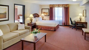 A hotel room with a bed, a sofa, a desk, and a chair.