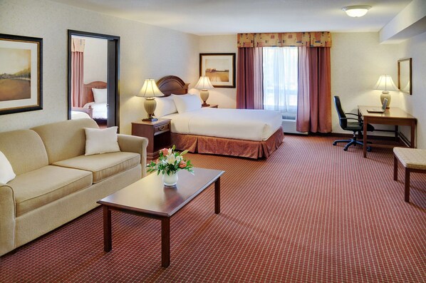 A hotel room with a bed, a sofa, a desk, and a chair. - Coast Grimshaw Hotel & Suites (Grimshaw)