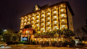 Um hotel de vários andares com varandas iluminadas e uma área de entrada coberta.