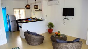 Ett modernt kök med kylskåp, diskho och en matplats med möbler i rotting.