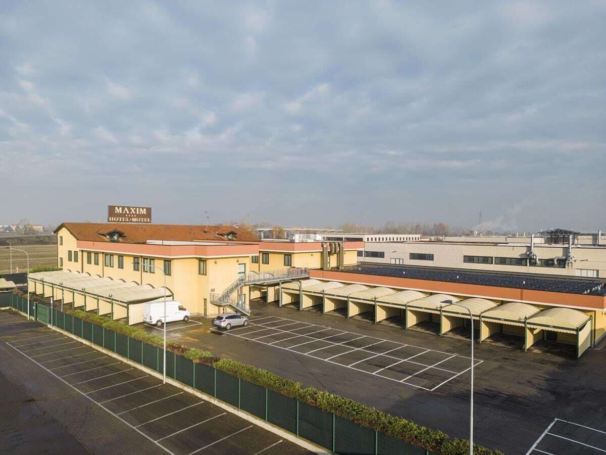 A MAXIM HOTEL-MOTEL with a parking lot, covered parking structures, and a building with a flat roof.