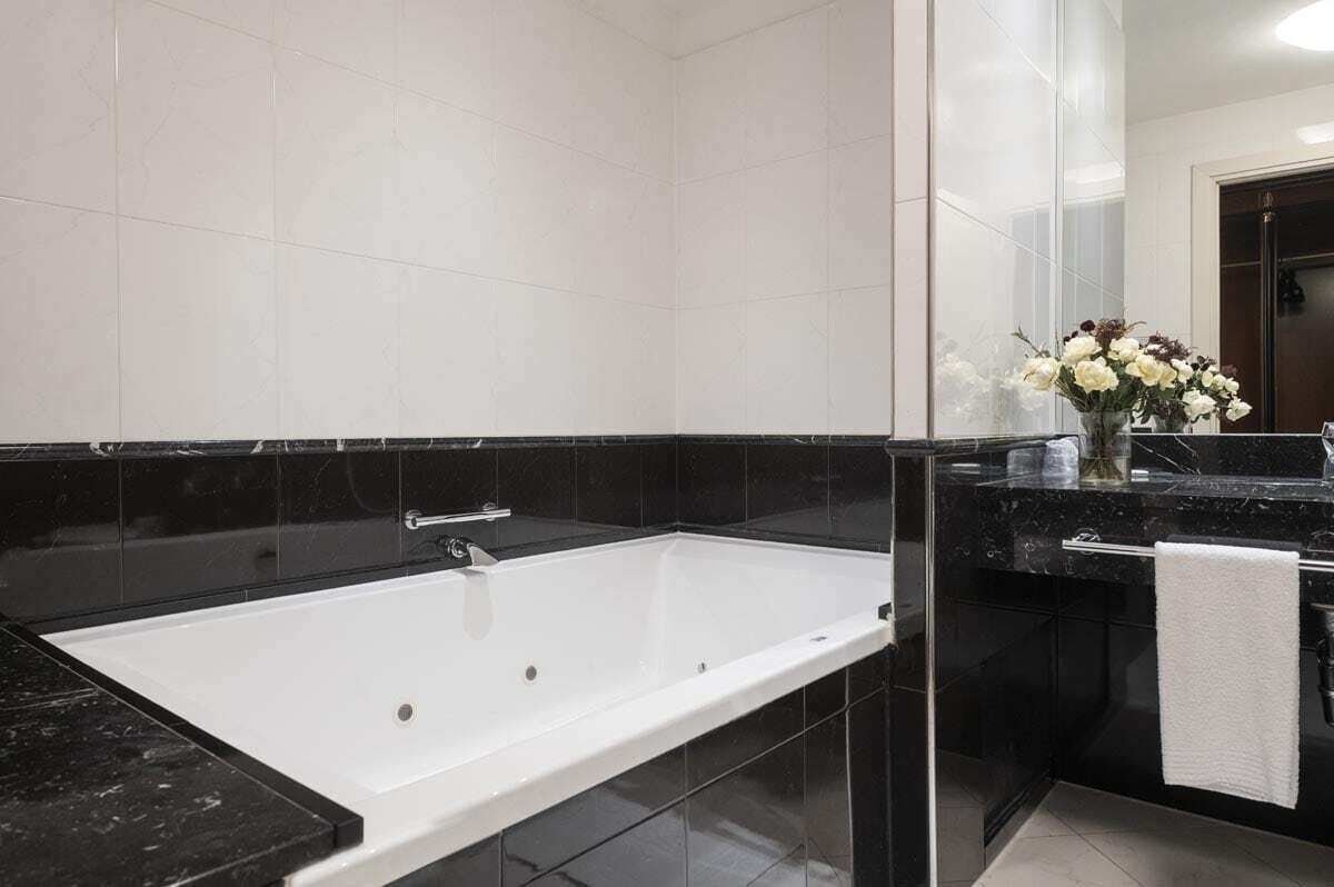 A modern bathroom with a large bathtub, a glass shower enclosure, and a marble countertop.
