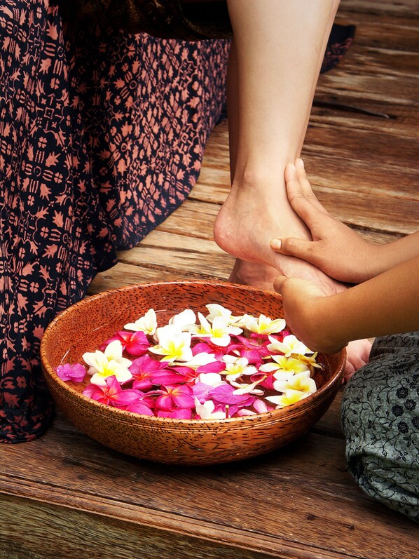 A wooden floor with a woven basket filled with flower petals.
