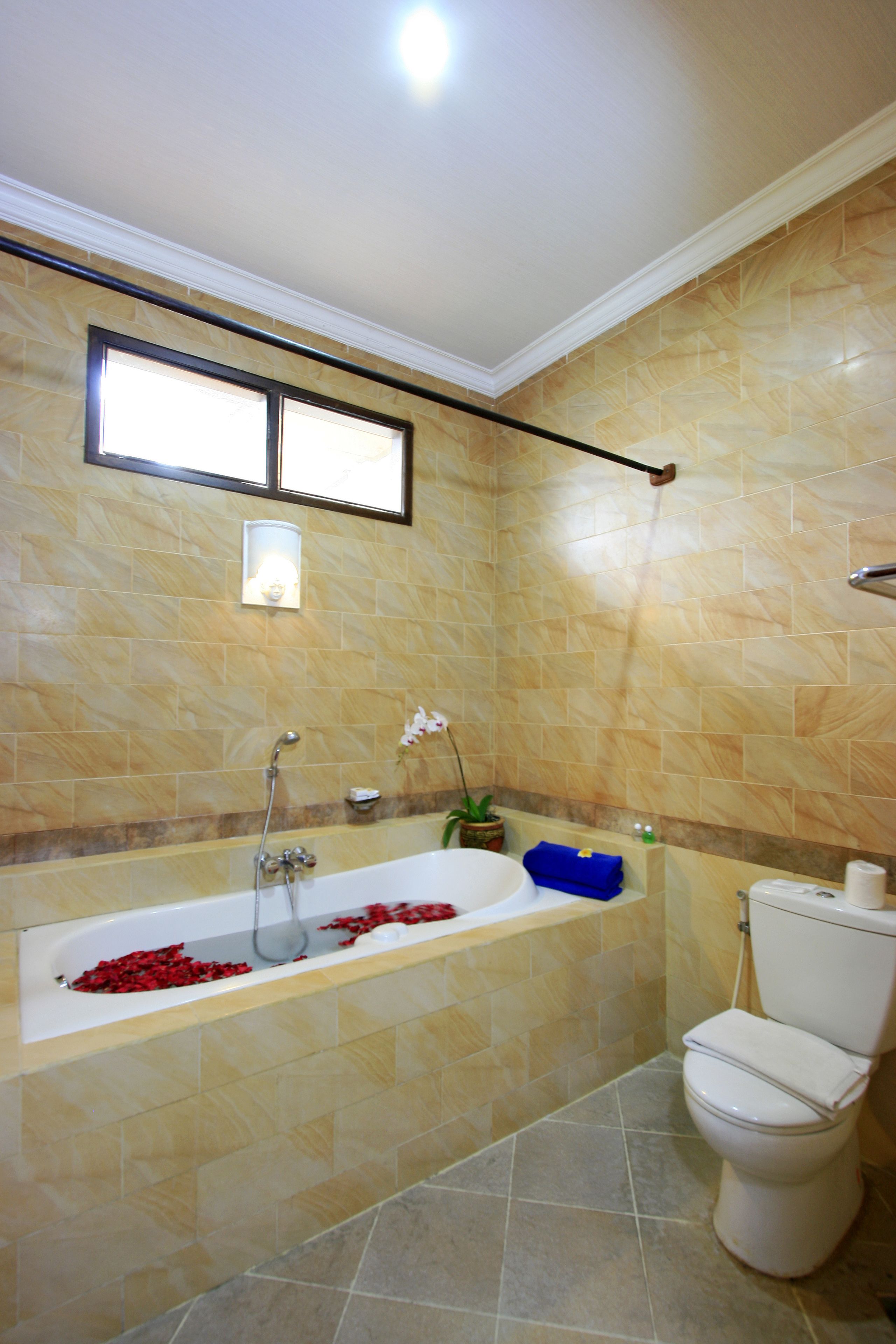 A bathroom with a bathtub, toilet, and a window above the sink.