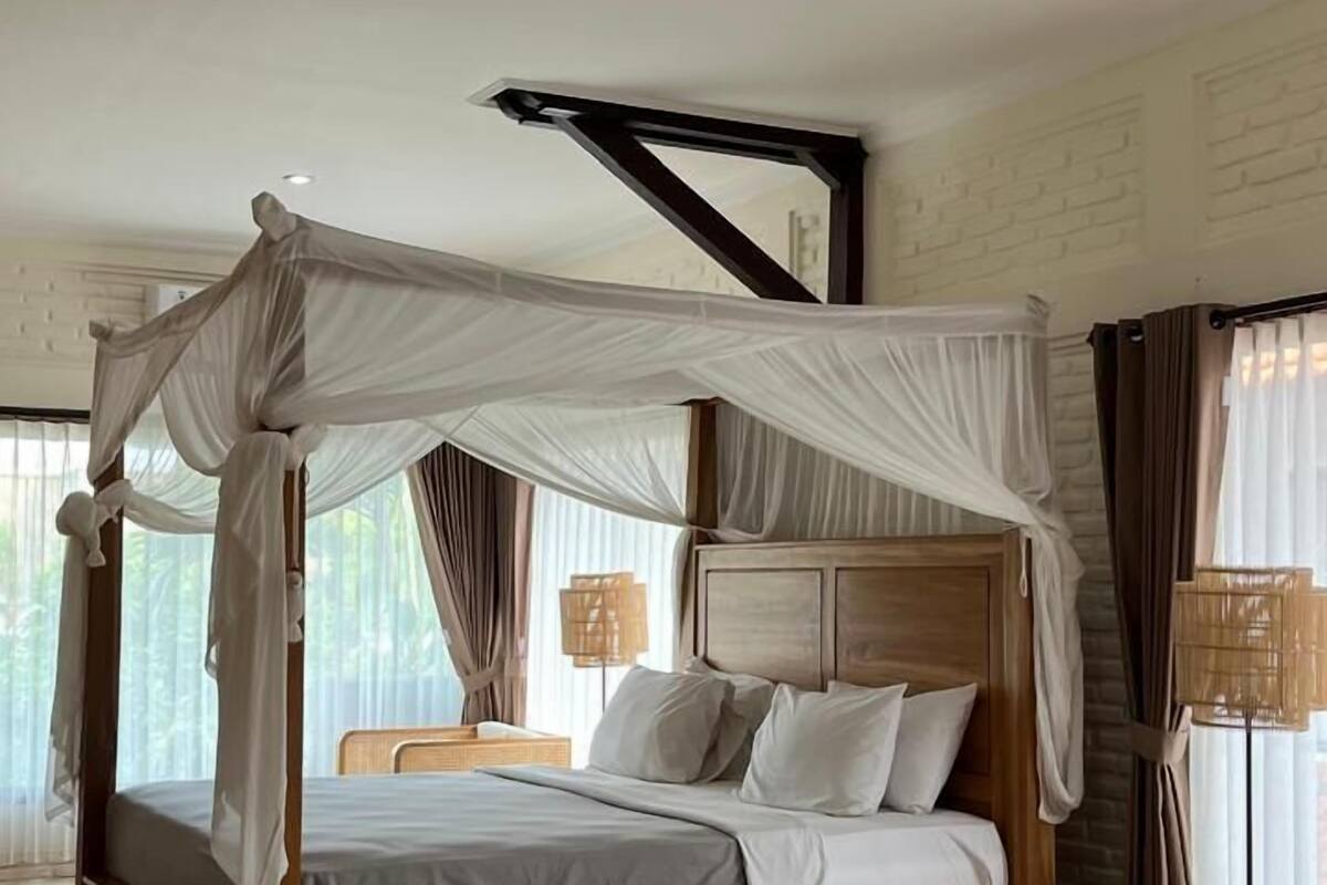 A wooden four-poster bed with a canopy, a bedside table, and a lamp.