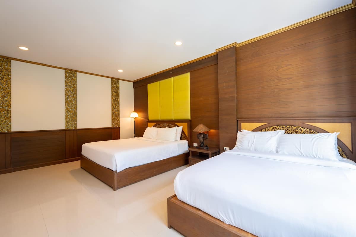 A hotel room with two beds, a nightstand, and a lamp.