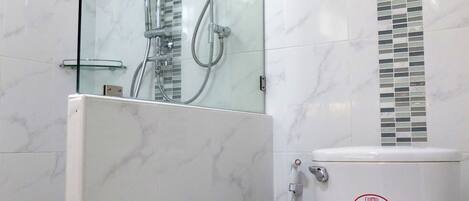 Une salle de bain moderne dotée d’une douche à parois de verre, de toilettes et d’un chauffe-eau mural.