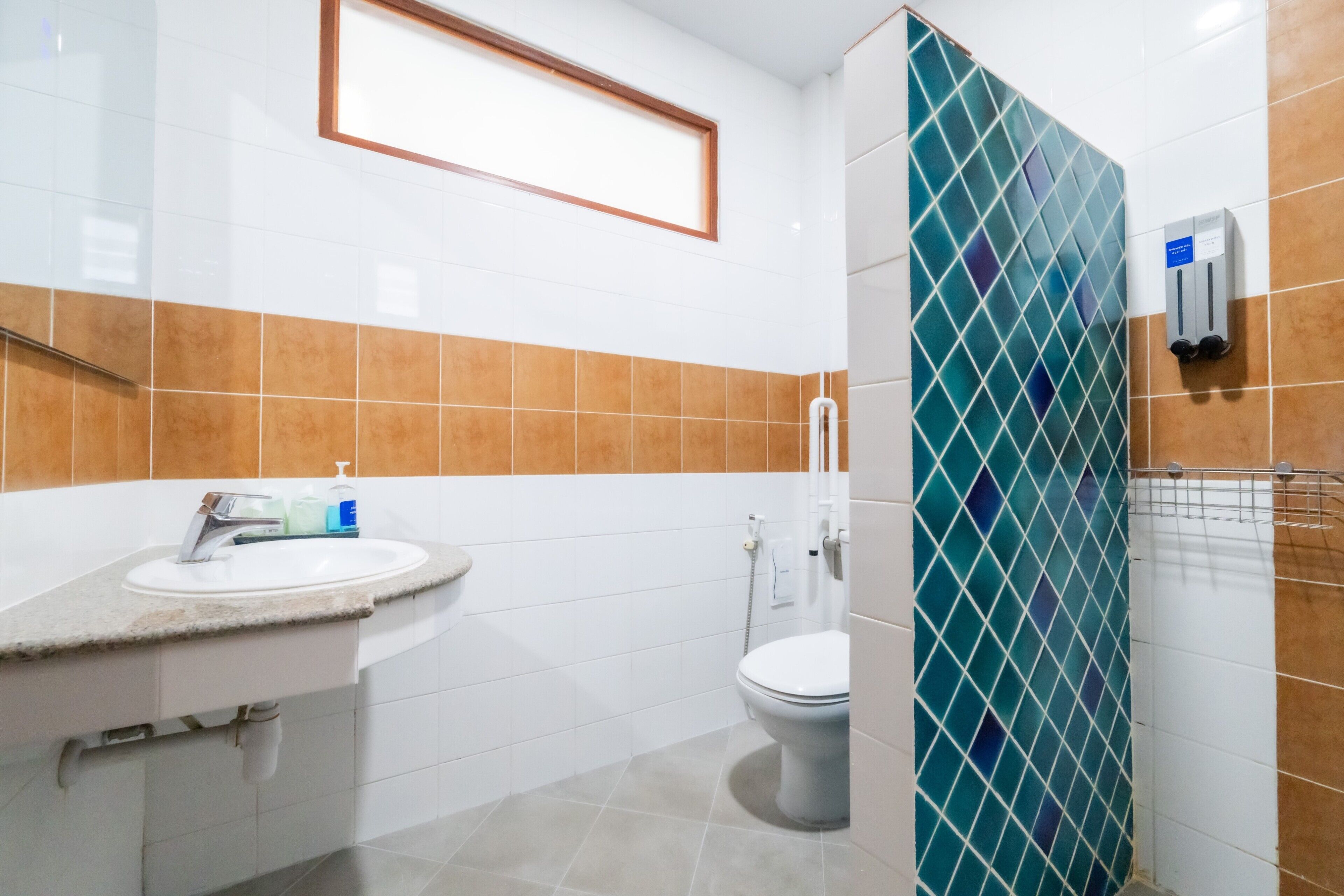 A bathroom with a sink, toilet, and a hand dryer.