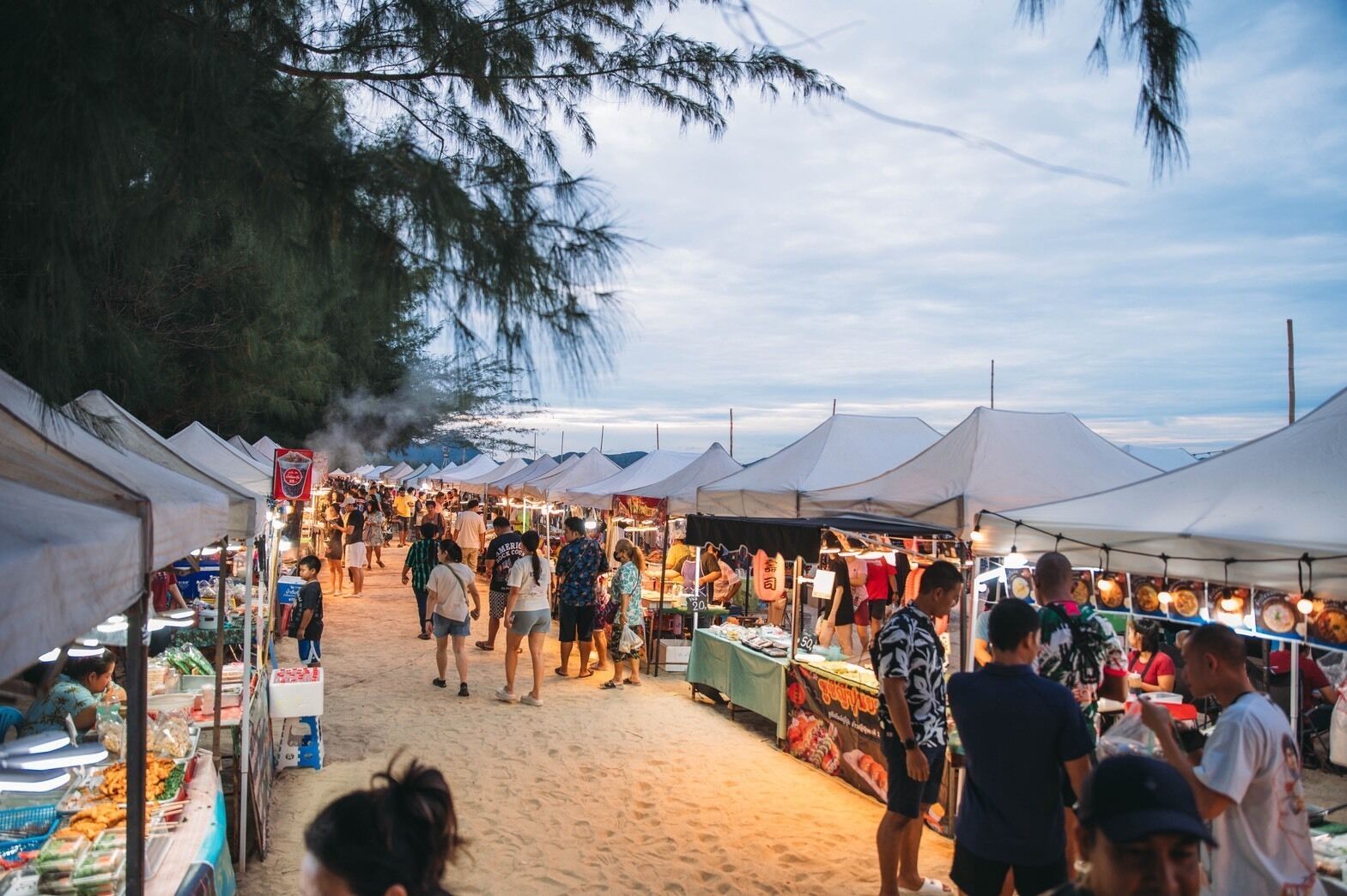A crowded outdoor market with tents and people browsing.