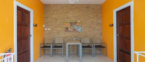 A room with a wooden door, a brick wall, a table with chairs, and a welcome mat.