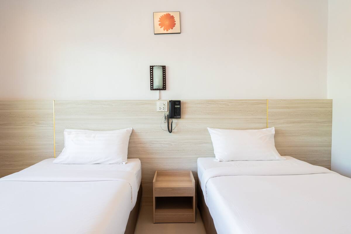 A hotel room with two beds, a bedside phone, and a small wooden nightstand.