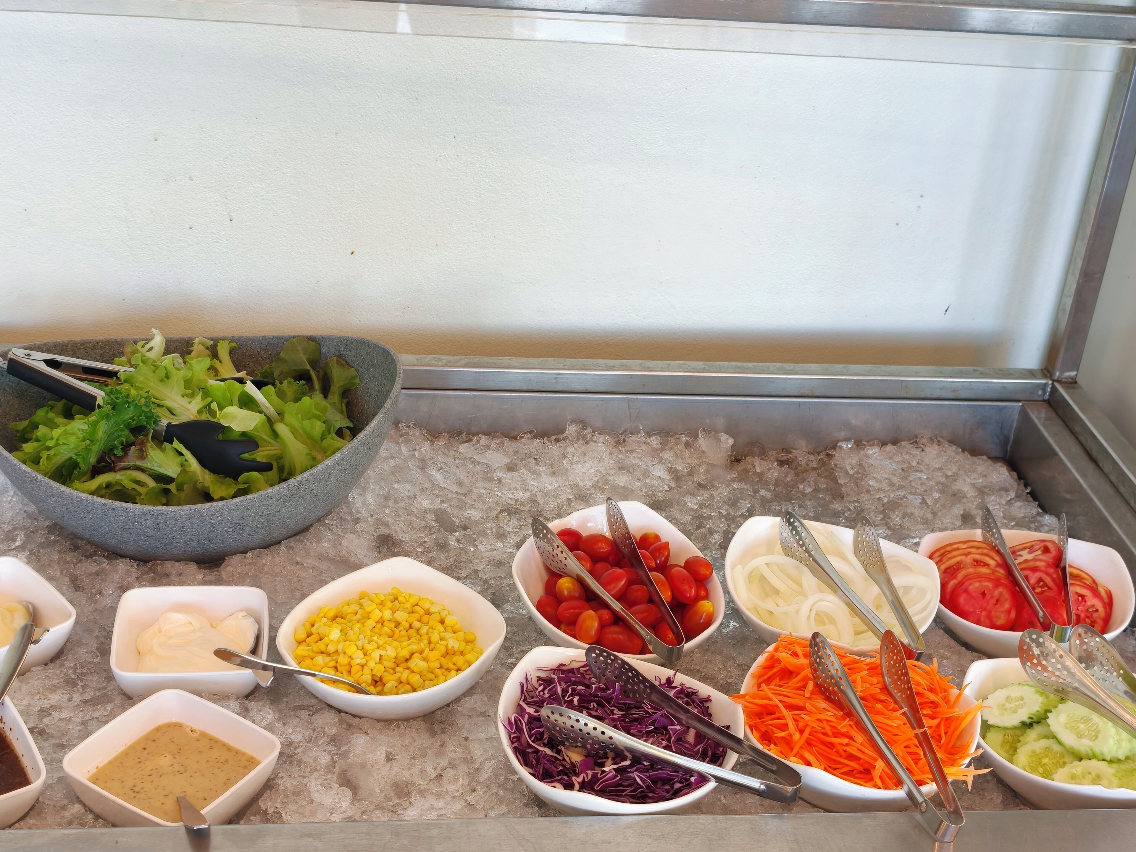 A buffet with various food items and utensils on a table.