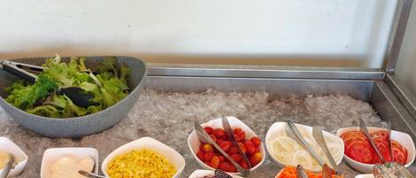 A buffet with various food items and utensils on a table.