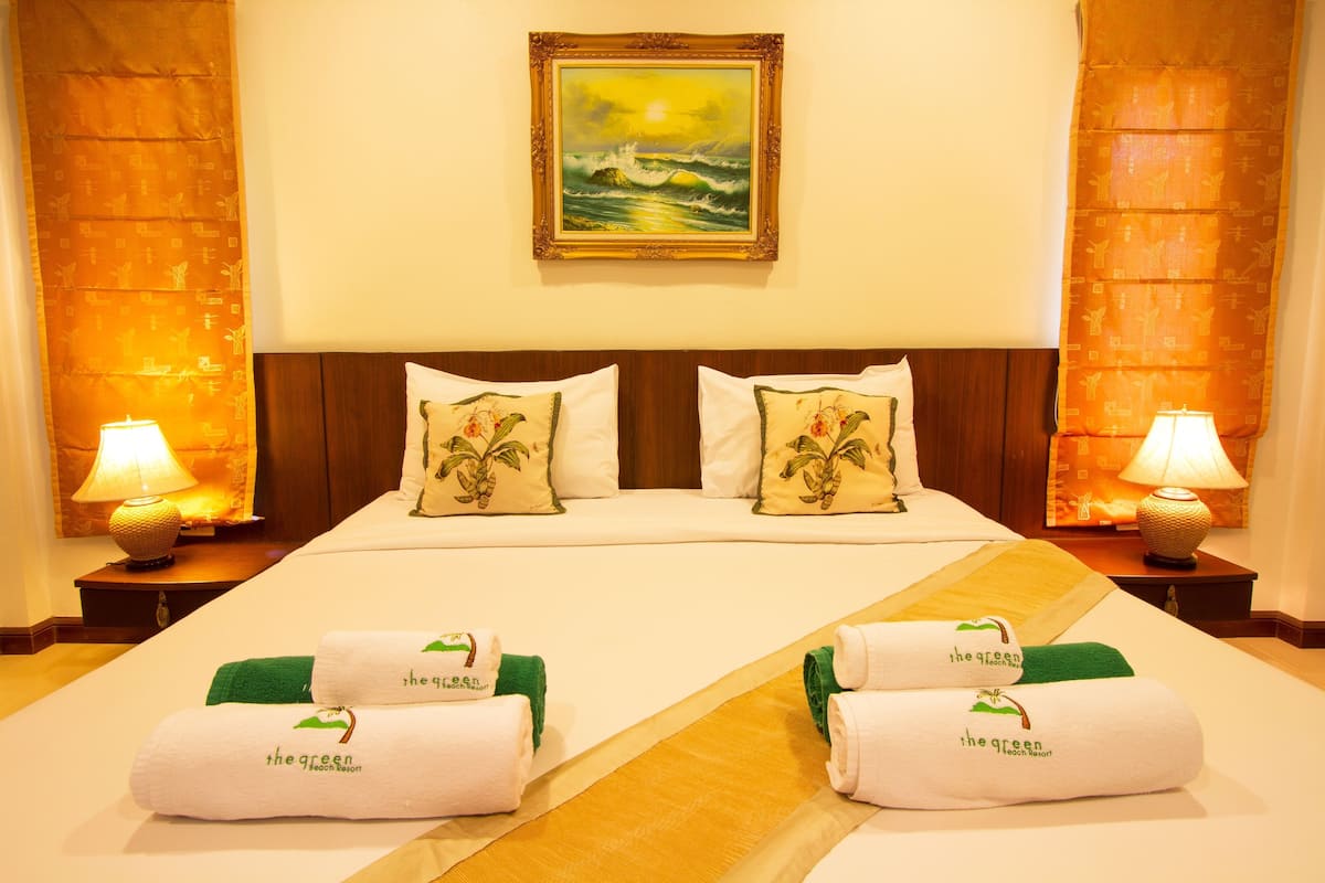 A hotel room with a bed, pillows, a painting, and towels.