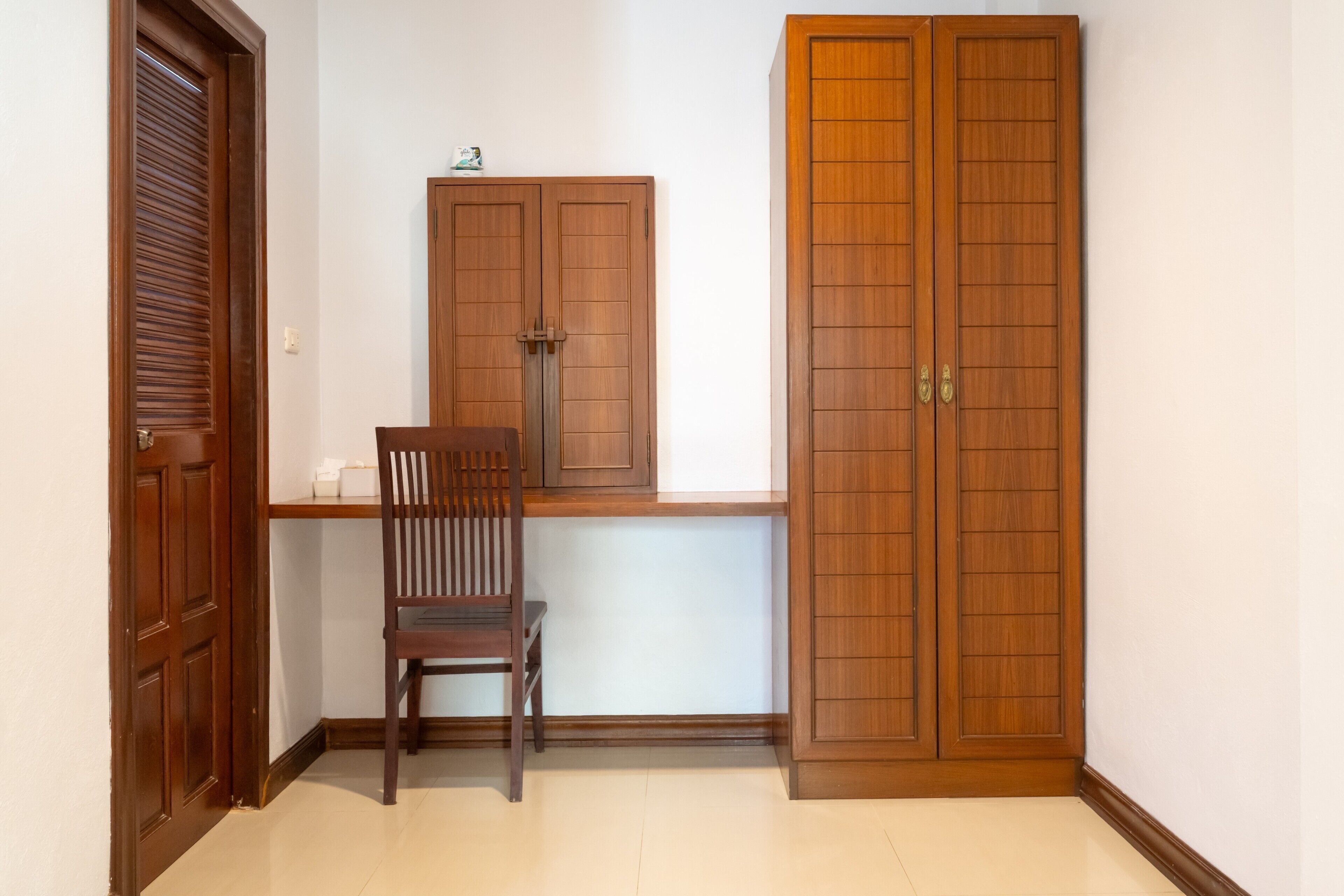 A room with a wooden desk, a chair, and two wardrobes.