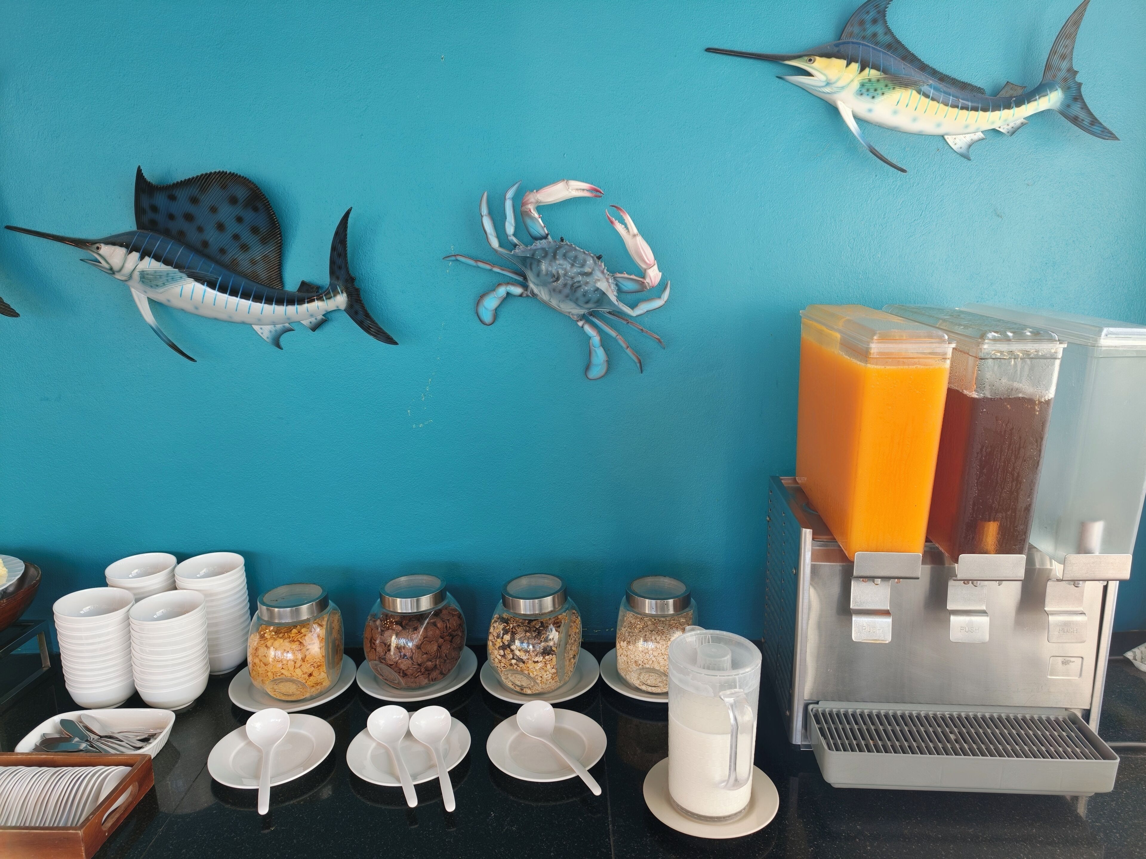 A breakfast bar with coffee dispensers, a juice dispenser, and various food containers.