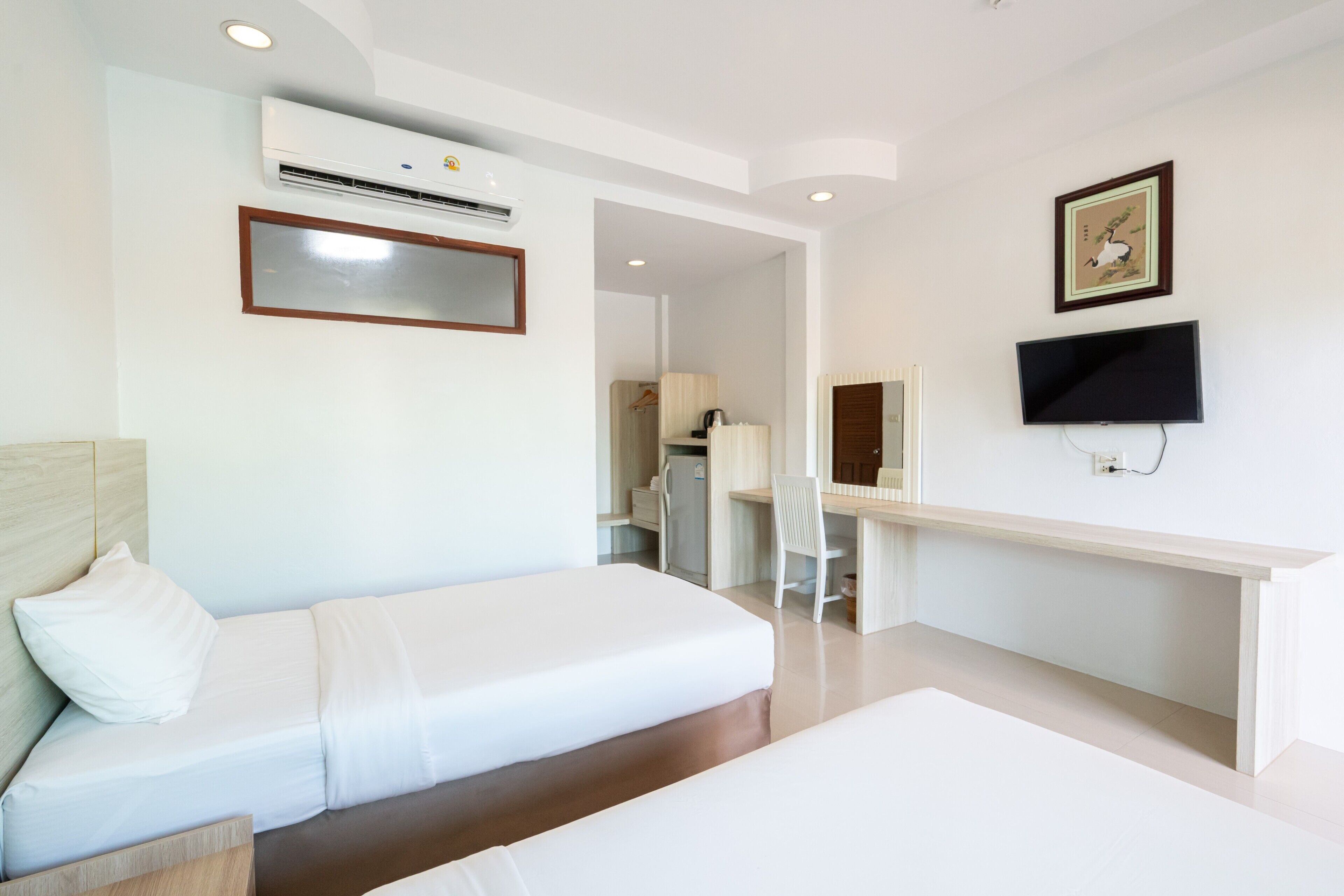 A hotel room with a bed, a desk, a chair, a television, and an air conditioning unit.